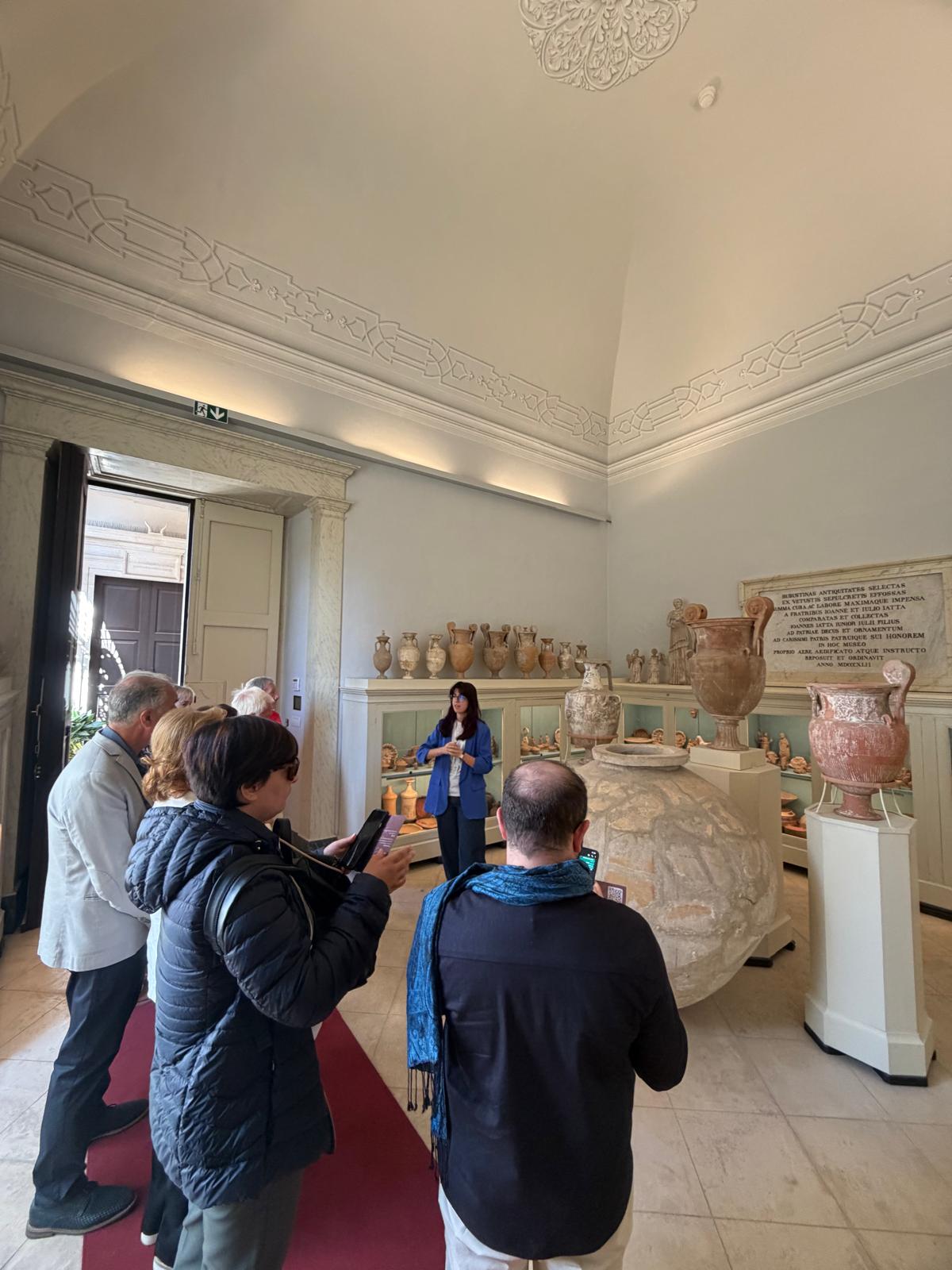 Guida e visitatori osservano reperti archeologici nelle sale del Museo Nazionale Jatta